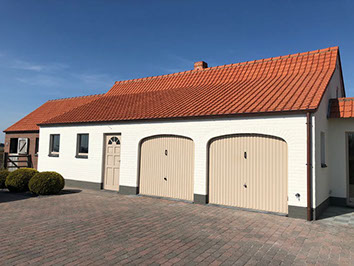 Witte woning met een oranjerood pannendak en twee garagepoorten, een project van Ramon BVBA